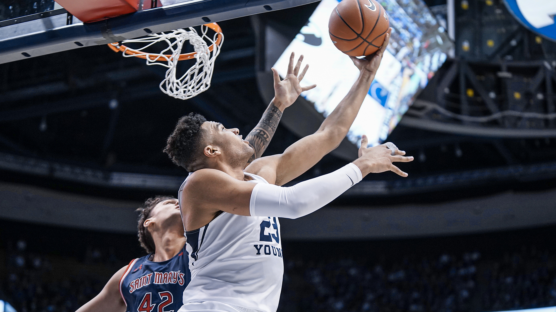 Yoeli Childs shoots the ball over his head under the basket with the right hand.