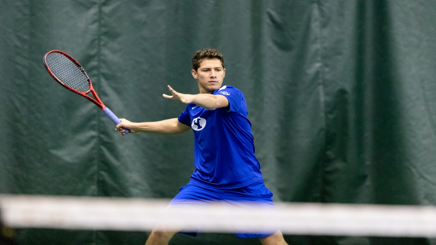 Tennis player in blue uniform prepares for a forehand shot.