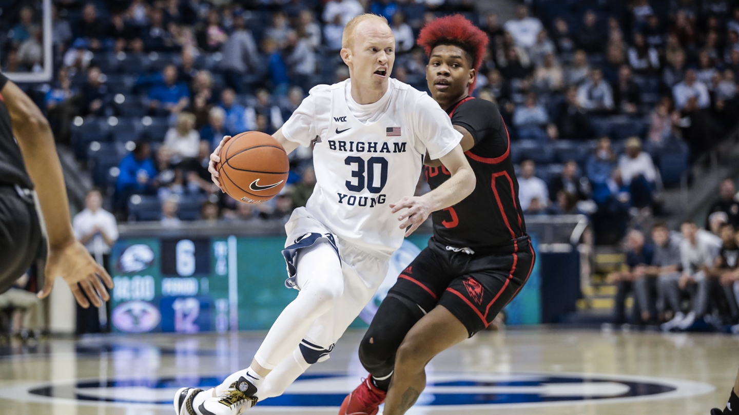 TJ Haws drives past a Southern Utah player with his right hand.