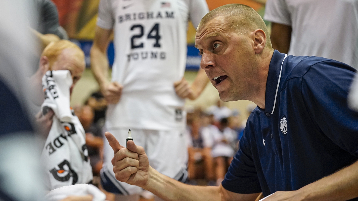 Mark Pope speaks with his team in the huddle against Kansas in Maui.