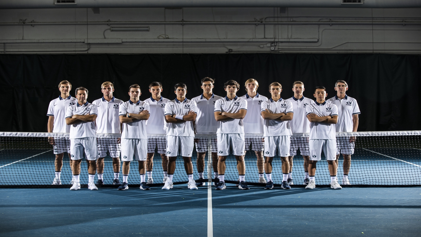 The BYU Men's Tennis Team poses in front of the net with the coaches.