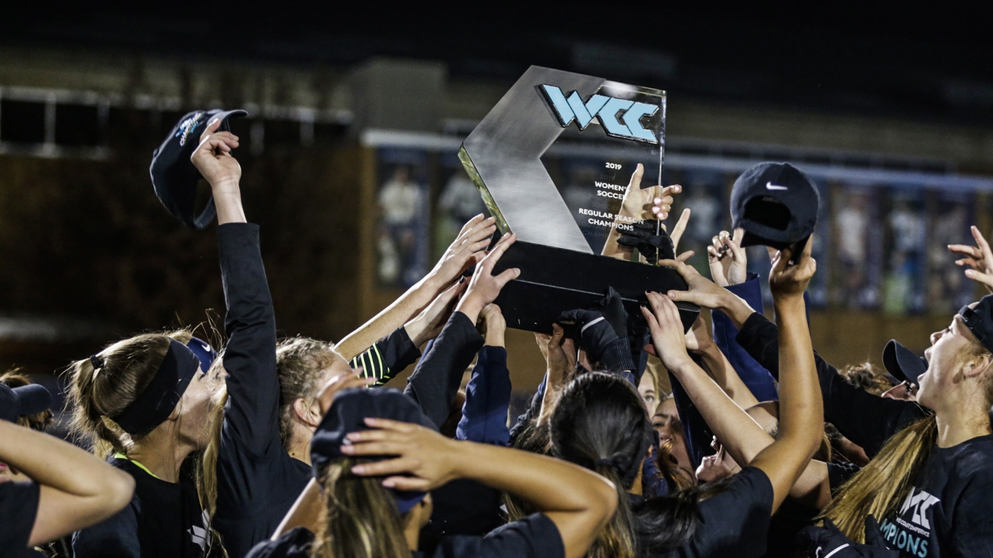 BYU soccer players holding up the 2019 WCC trophy