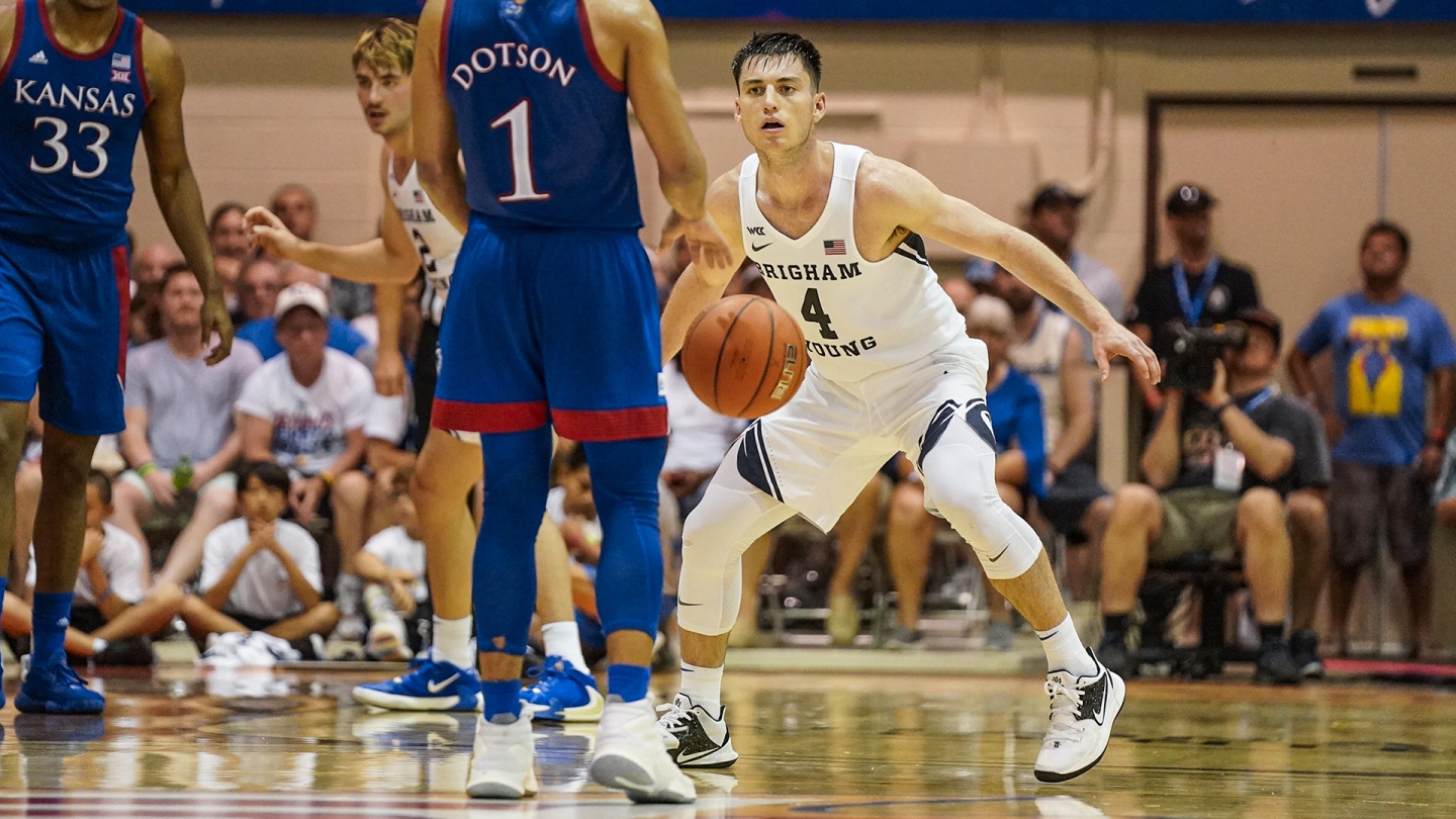 Alex Barcello in a defensive stance while a Kansas player dribbles the basketball.