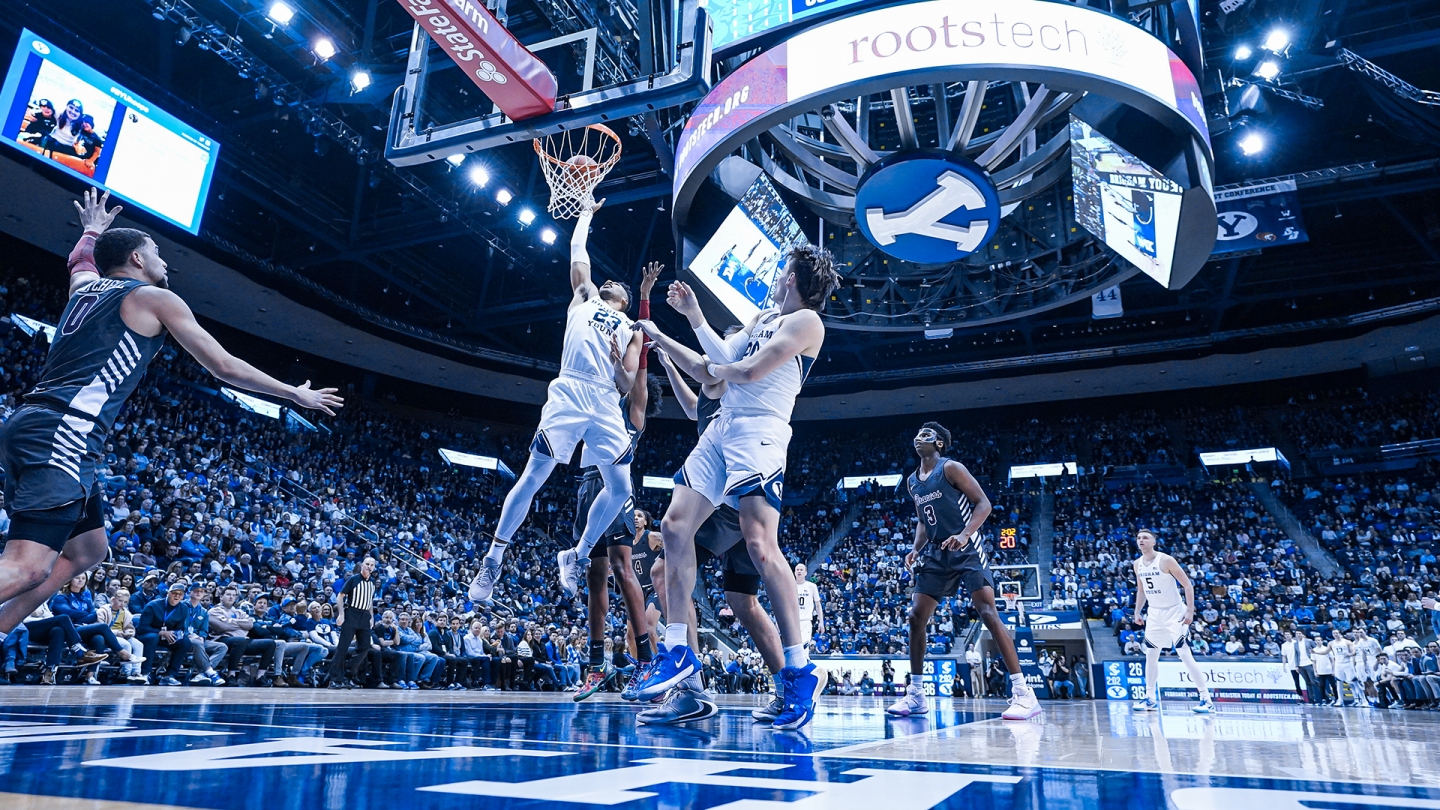 Yoeli Childs tips the ball in the basket against Santa Clara while several players look on.