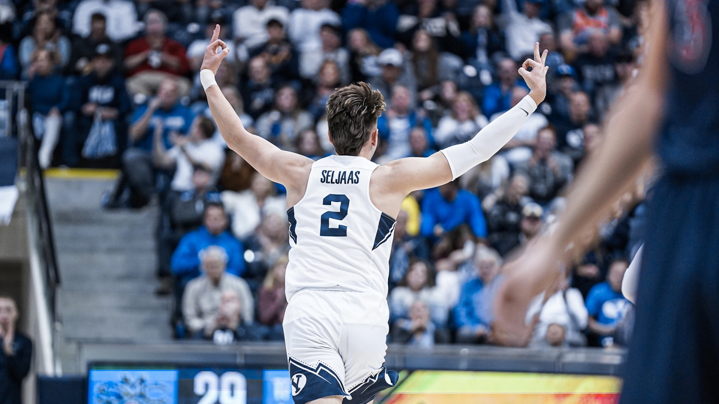 Zac Seljaas holds up three fingers on both hands while running down the court, celebrating a made 3-pointer.