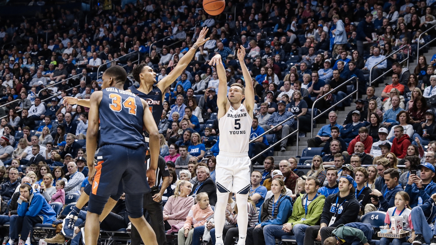 Jake Toolson shoots a 3-pointer from the wing while a Pepperdine stretches out to try and block the shot.