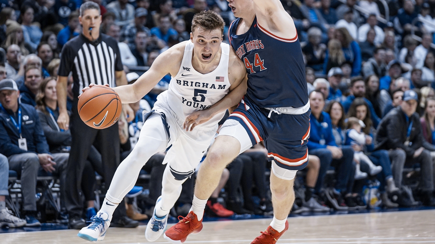 Jake Toolson dribbles towards the basket with his right hand while #44 from Saint Mary's defends.