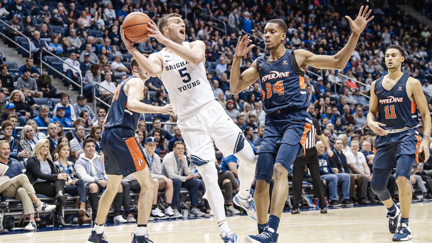 Jake Toolson looks to pass while falling away and a Pepperdine player defends.